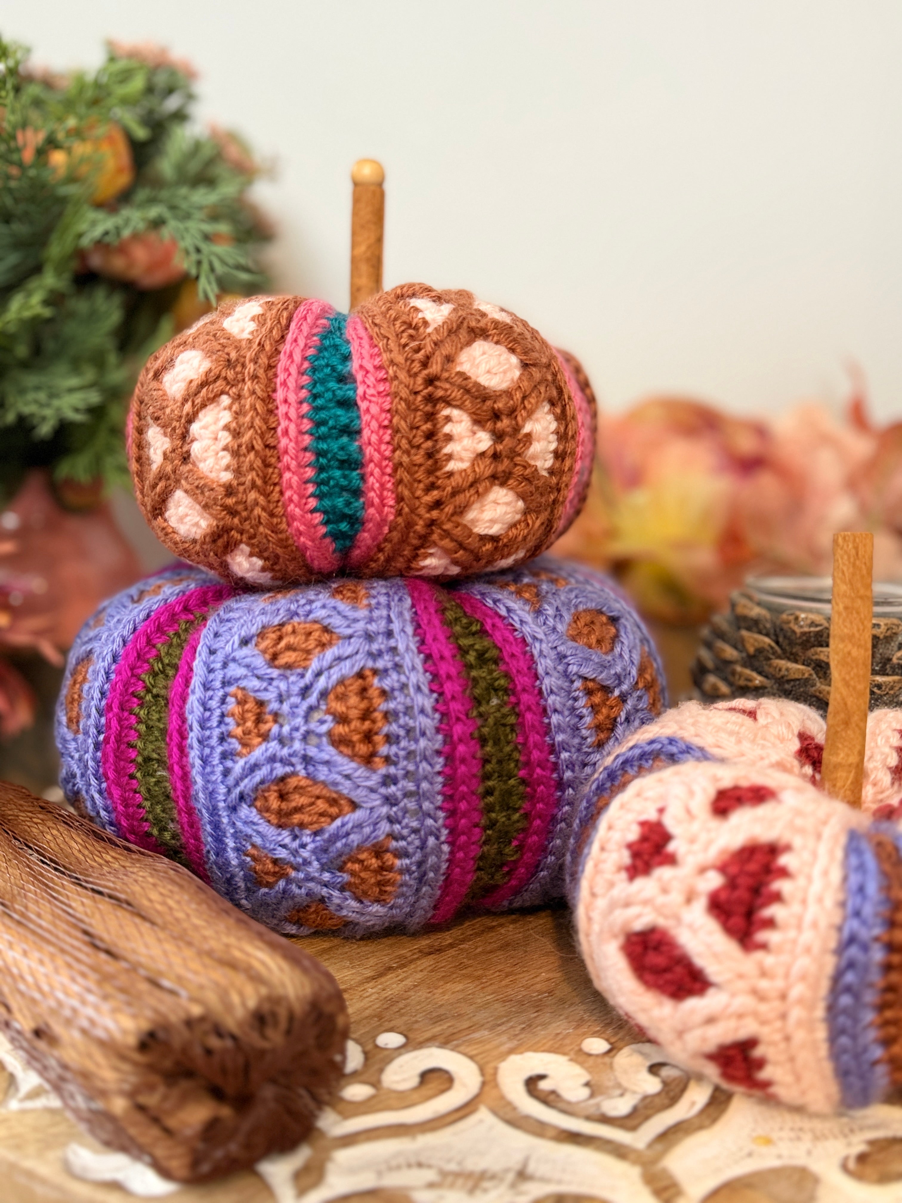 Stacked trio of mosaic crochet pumpkins in pink, brown, and purple colorways