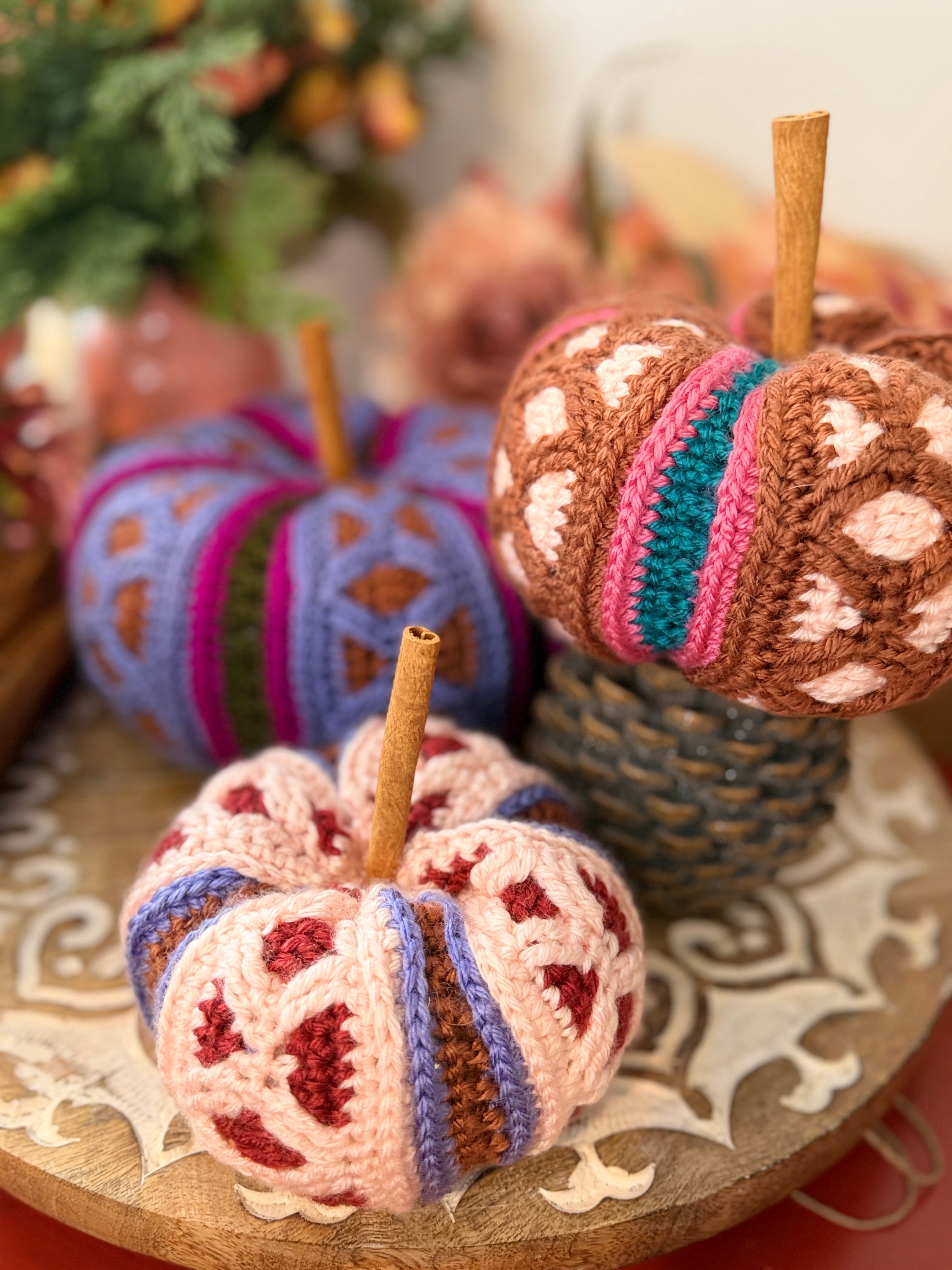 Stacked trio of mosaic crochet pumpkins in pink, brown, and purple colorways