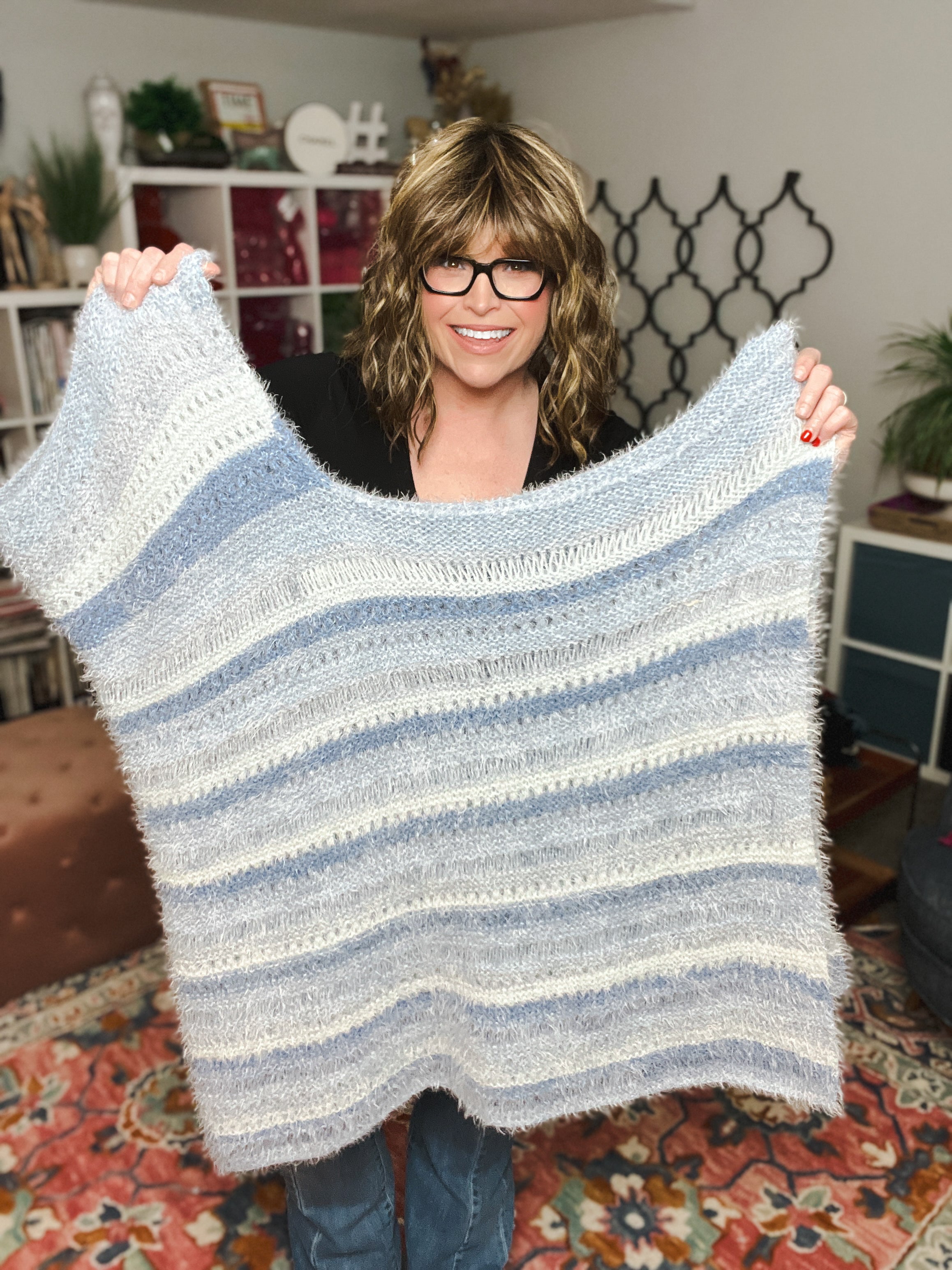 Woman holding up oversized knit poncho with relaxed fit
