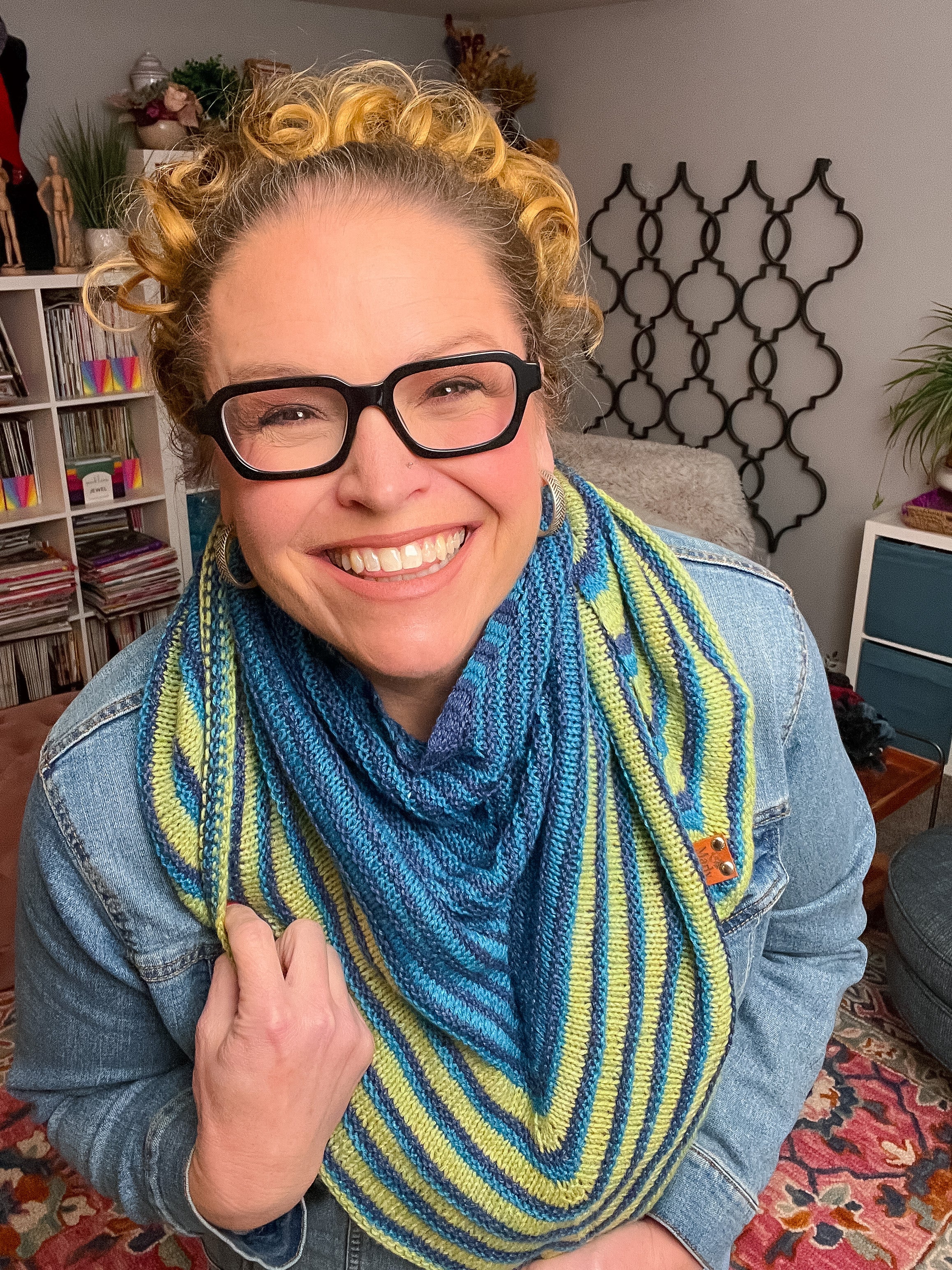 Person wearing a blue and green striped scarf in a room with books and decor. Make It Mine Knit Shawl triangle shawl pattern garter stitch striped knit wrap