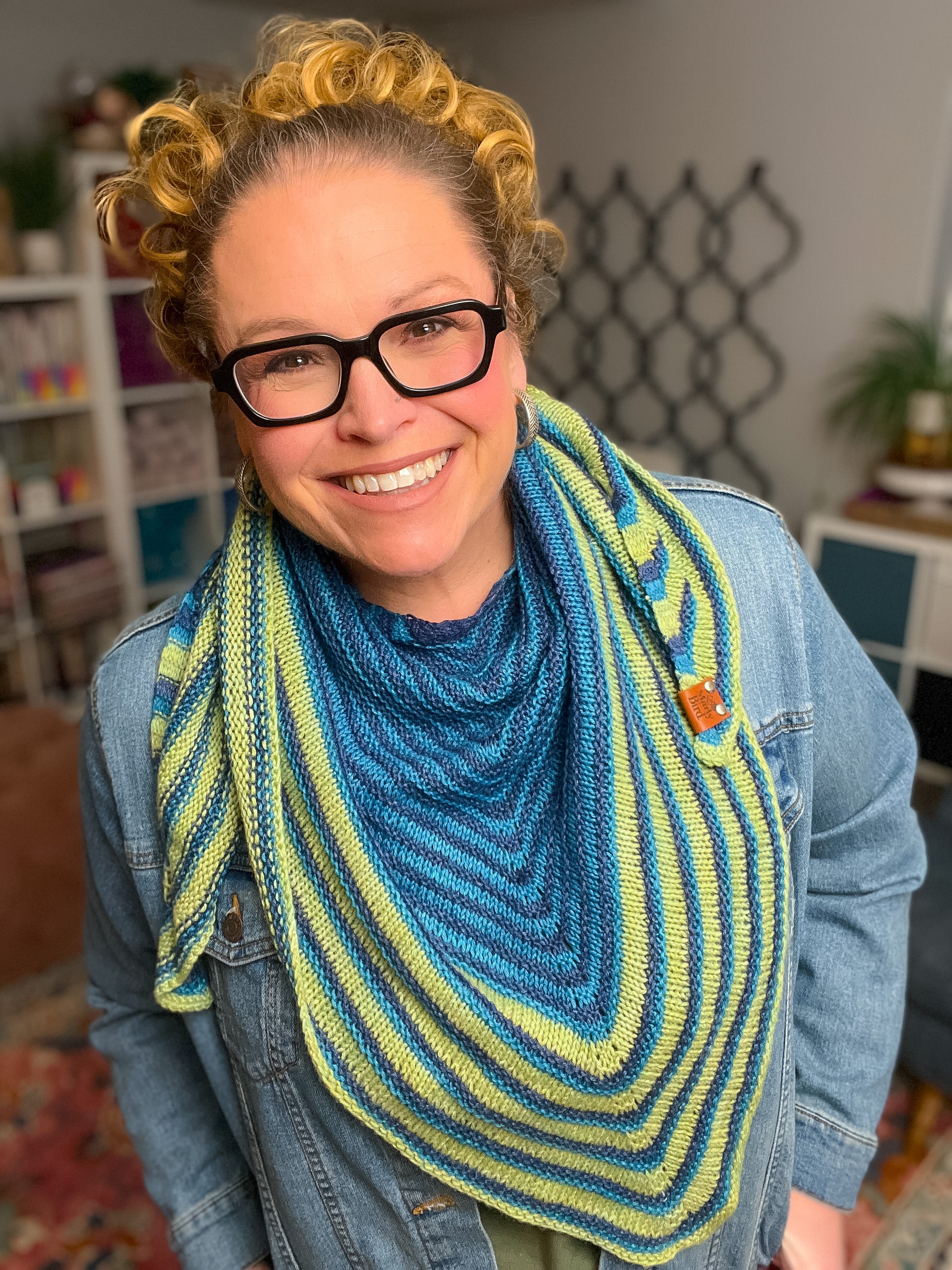 Person wearing a blue and green knitted scarf in an indoor setting. Make It Mine Knit Shawl triangle shawl pattern garter stitch striped knit wrap