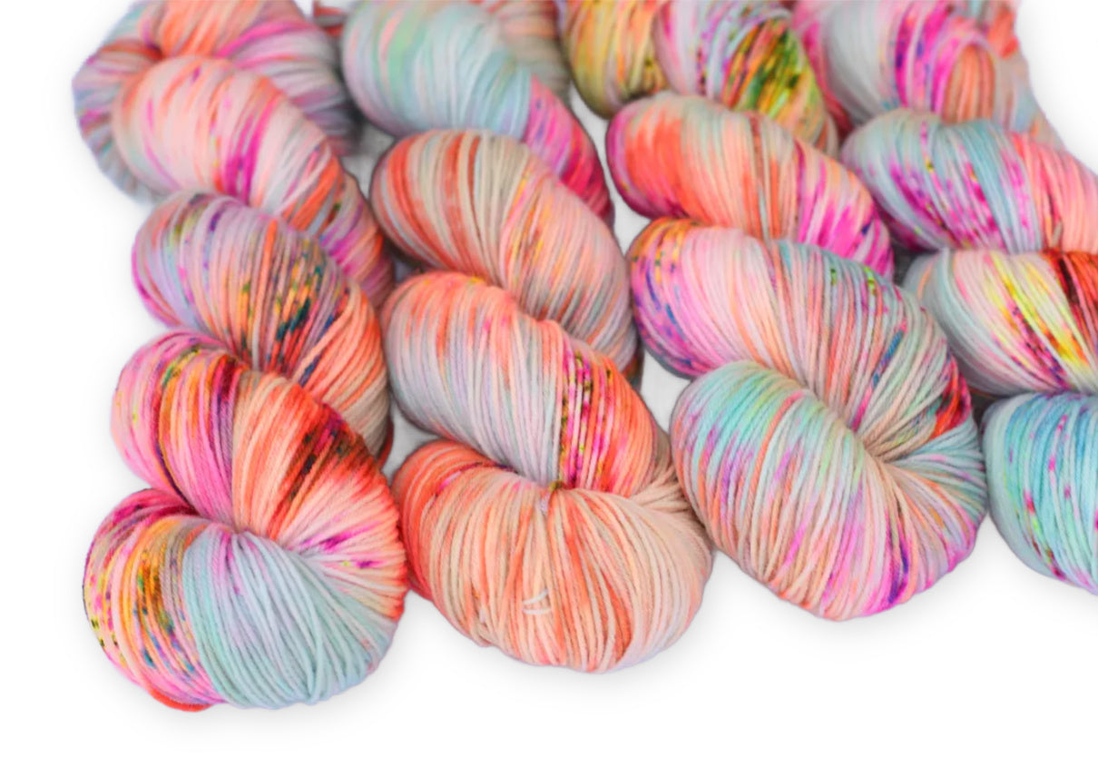 Skeins of Still Not Angry yarn in pastel pink, peach, mint, and gray with bright multicolor speckles.