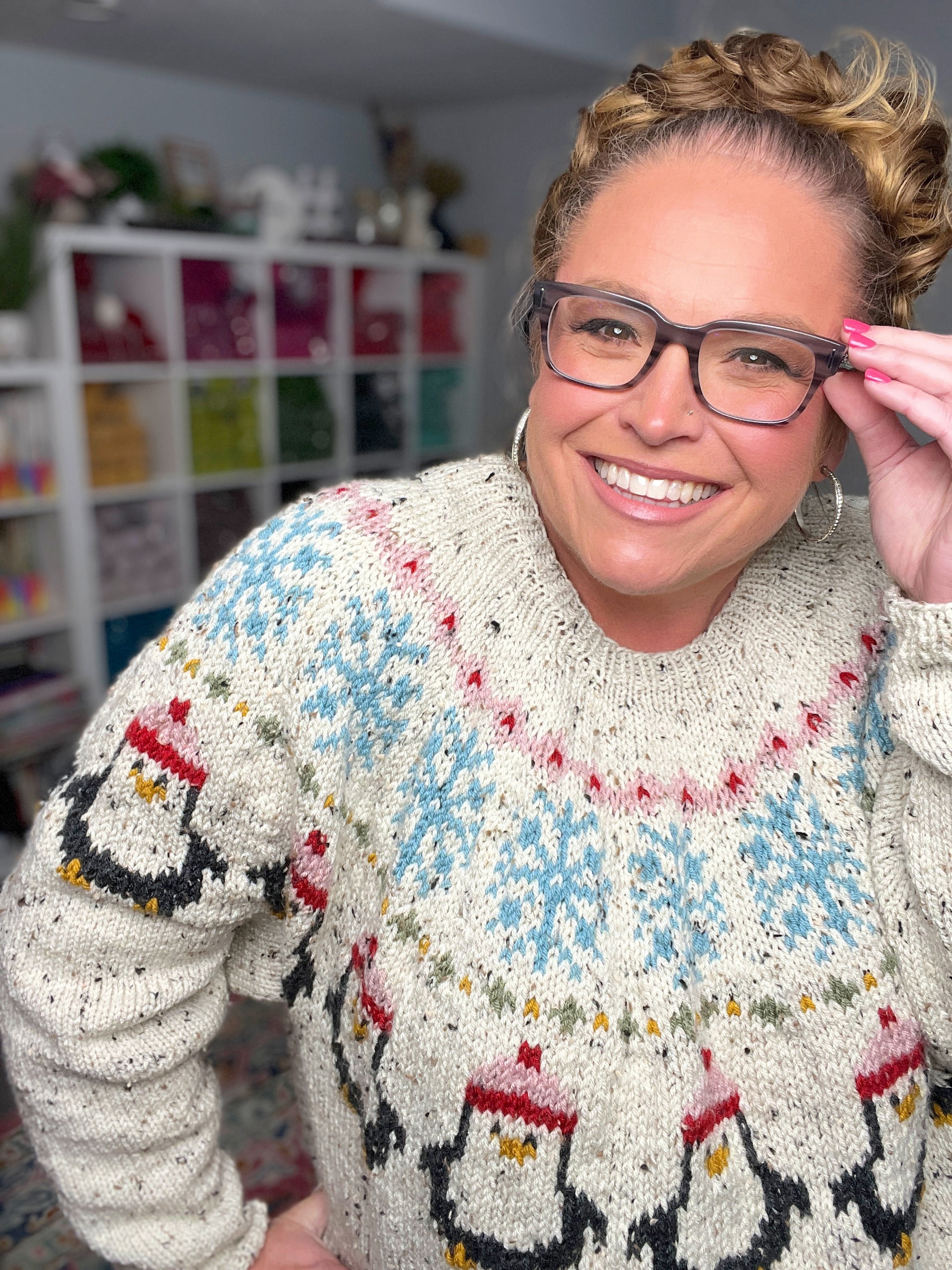 Person wearing a patterned sweater with penguin design in a room with shelves in the background