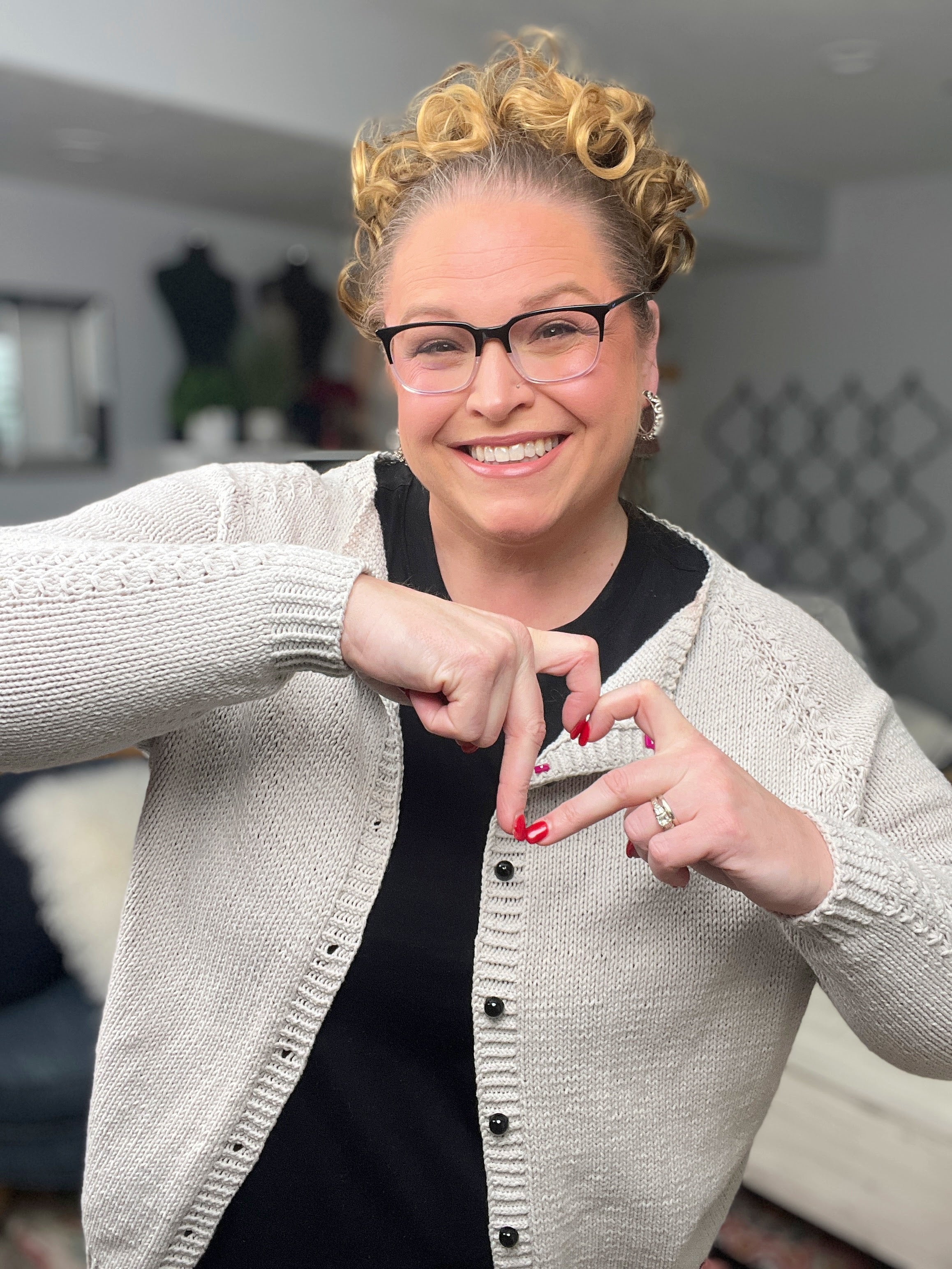 Woman making a heart shape with her hands in a living room setting