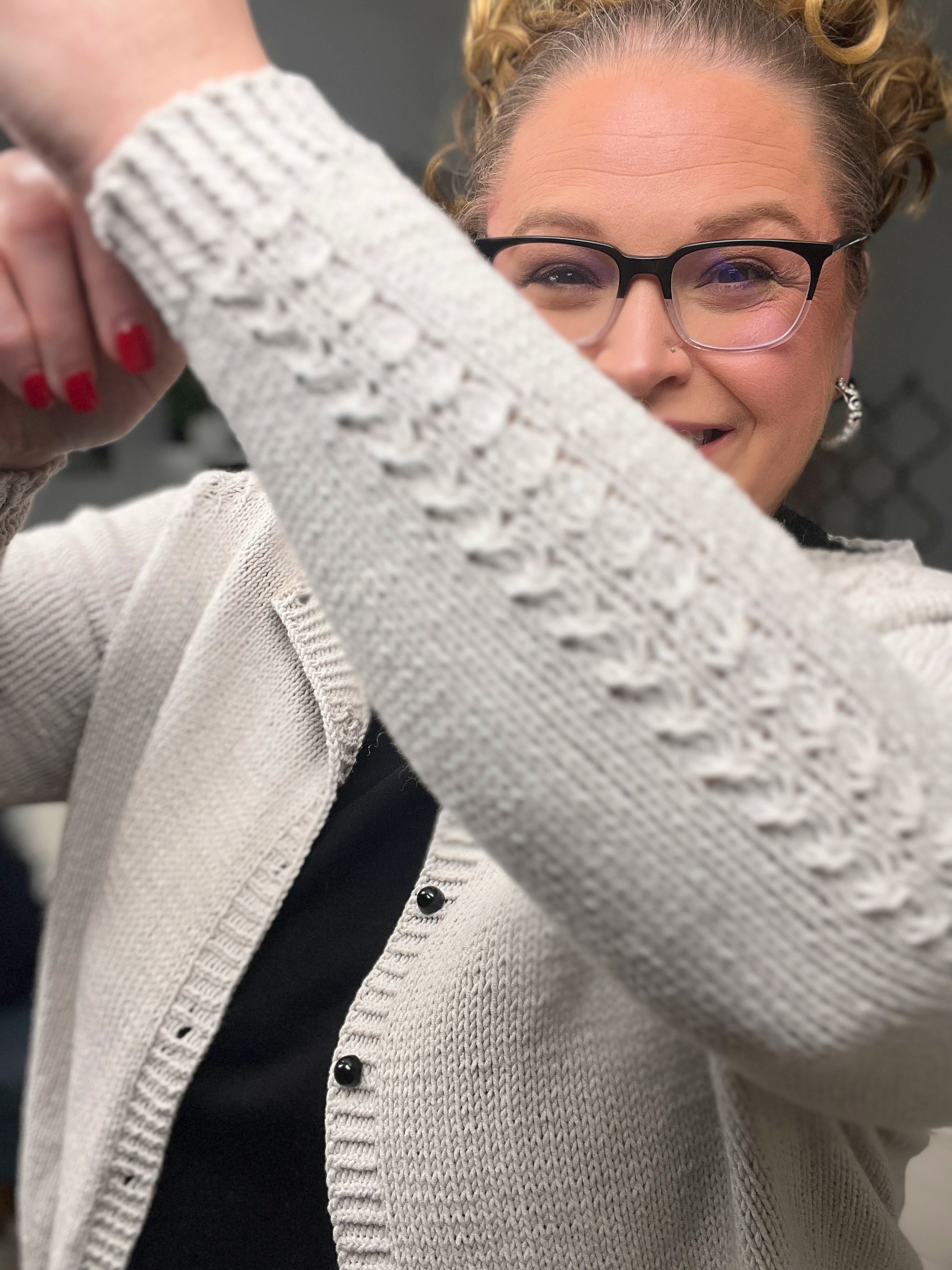 Woman wearing a light gray cardigan with a textured pattern