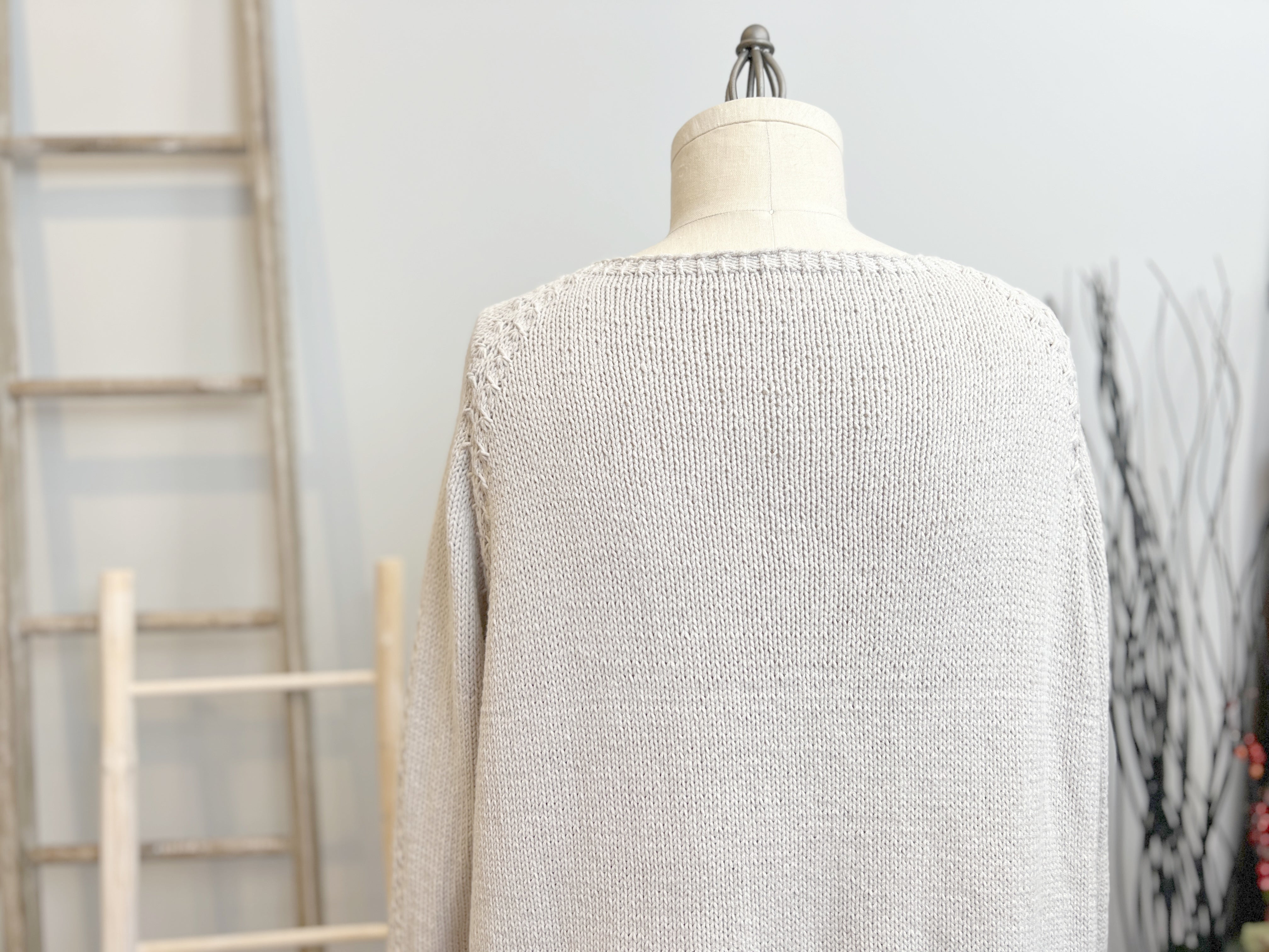 Light gray textured sweater on a mannequin with a neutral background