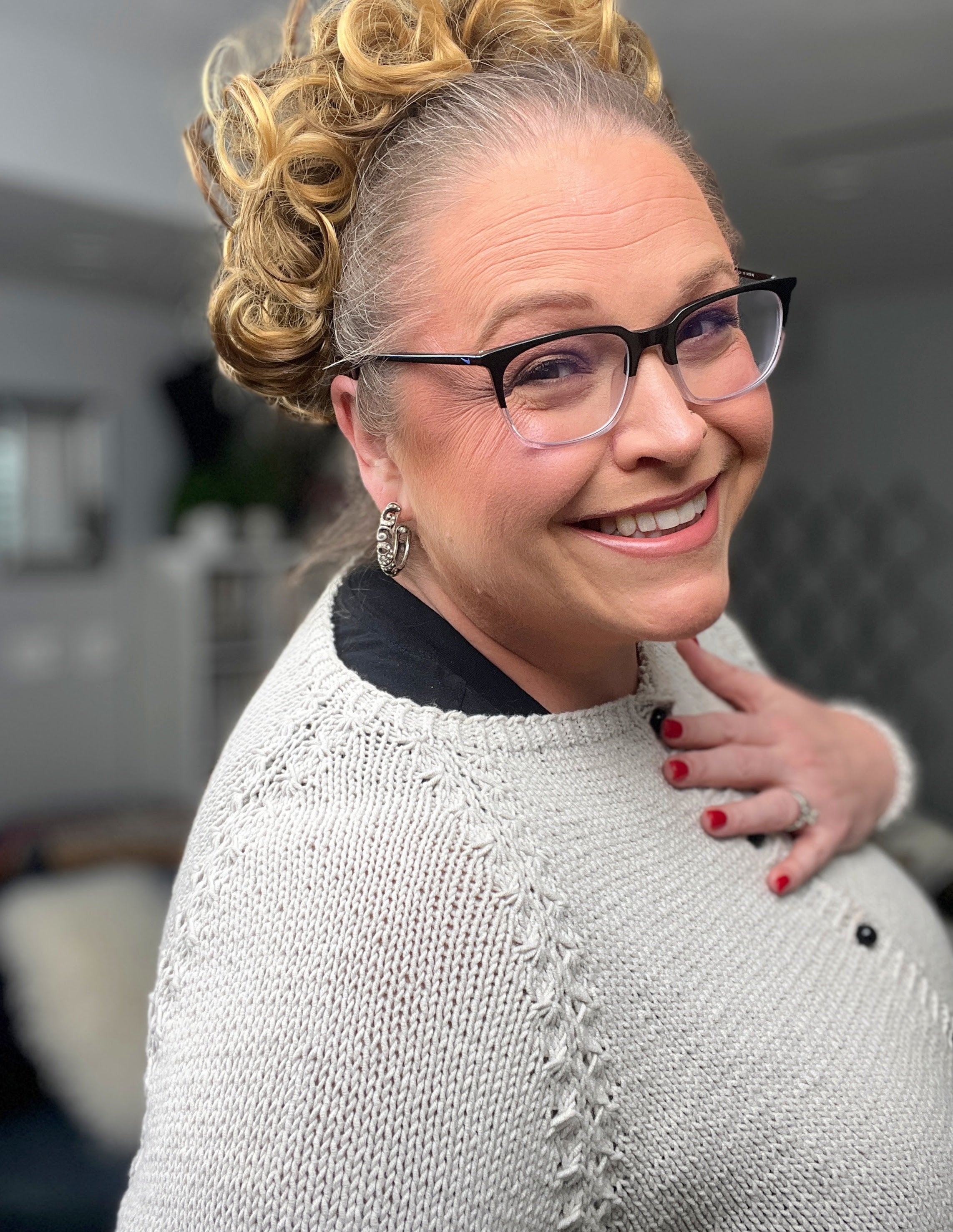 Woman wearing glasses and a gray sweater with a blurred background