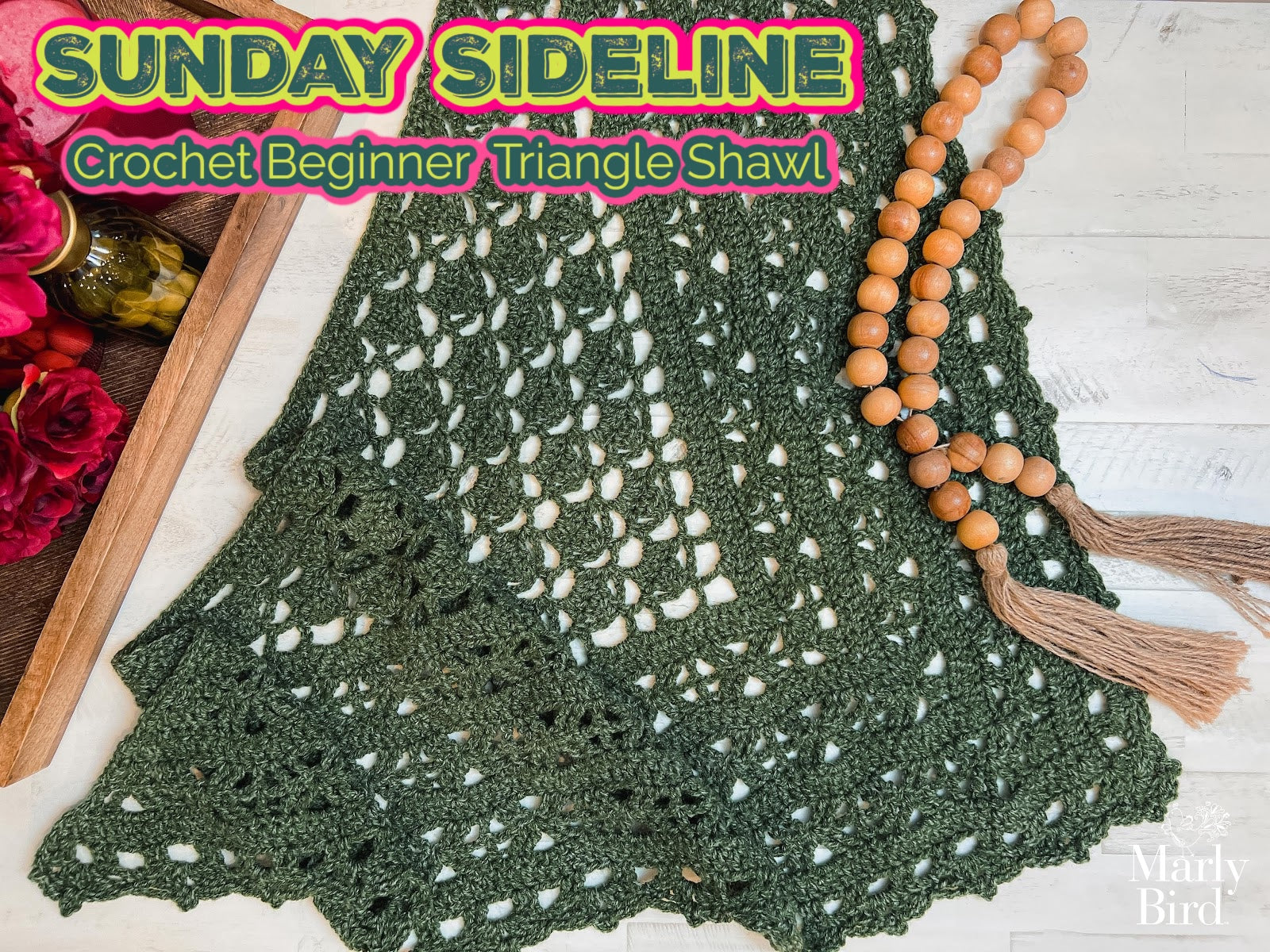 Sunday Sideline Crochet Shawl Pattern – Easy One Skein Lace Triangle Wrap is shown on a light surface near a wooden bead tassel and flowers. Overlaid text reads “SUNDAY SIDELINE Crochet Beginner Triangle Shawl.”.