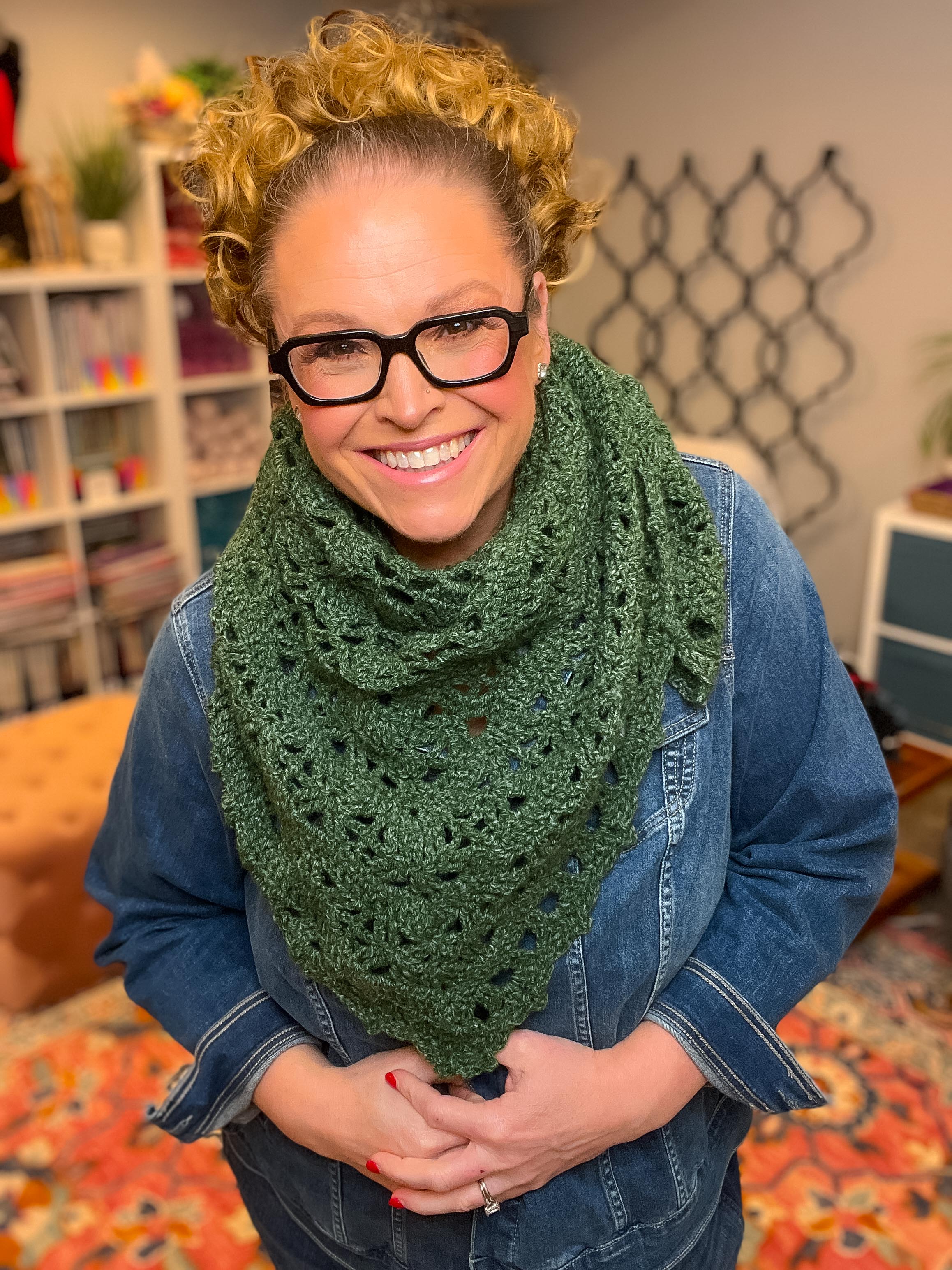 Woman wearing a green crochet triangle shawl. Showcasing the crochet lace stitches wearing it bandana style